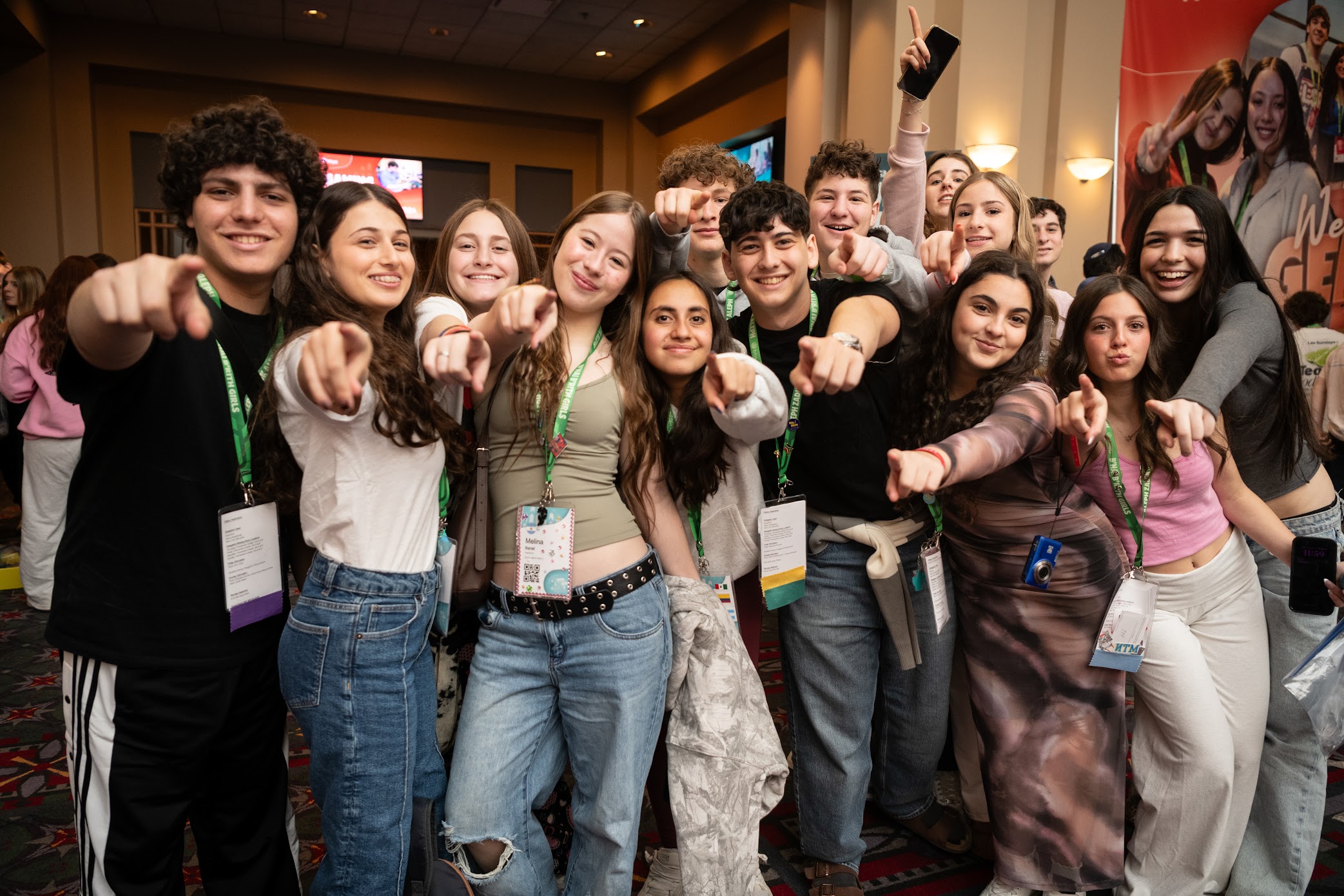 A diverse crowd of people celebrating at a concert, raising their hands and cheering.