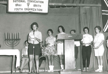 A diverse crowd of people celebrating at a concert, raising their hands and cheering.