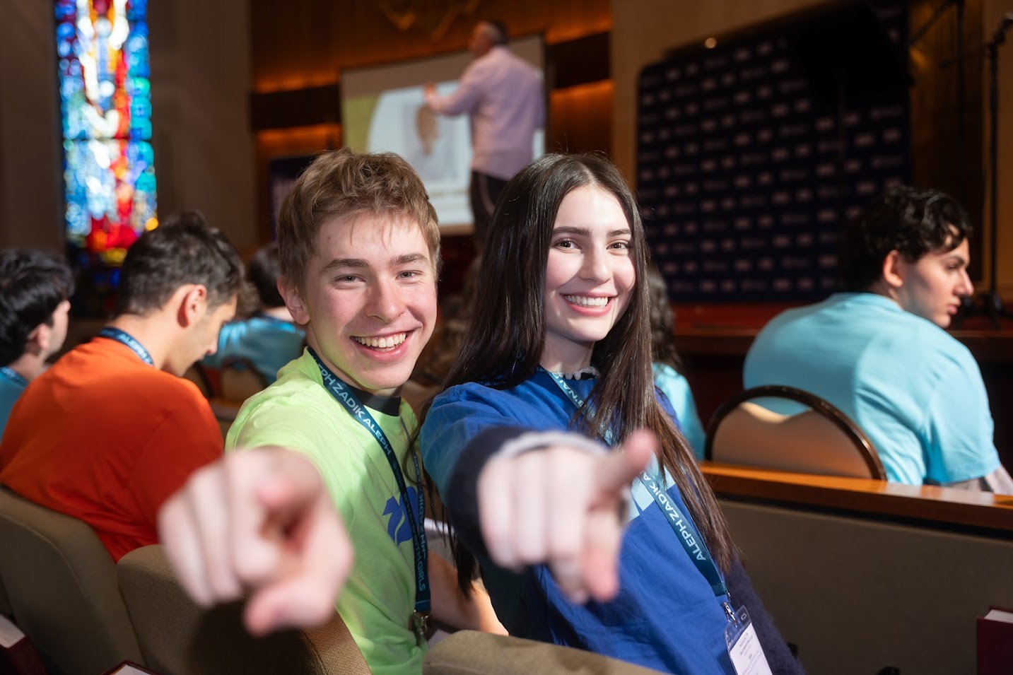 A diverse crowd of people celebrating at a concert, raising their hands and cheering.