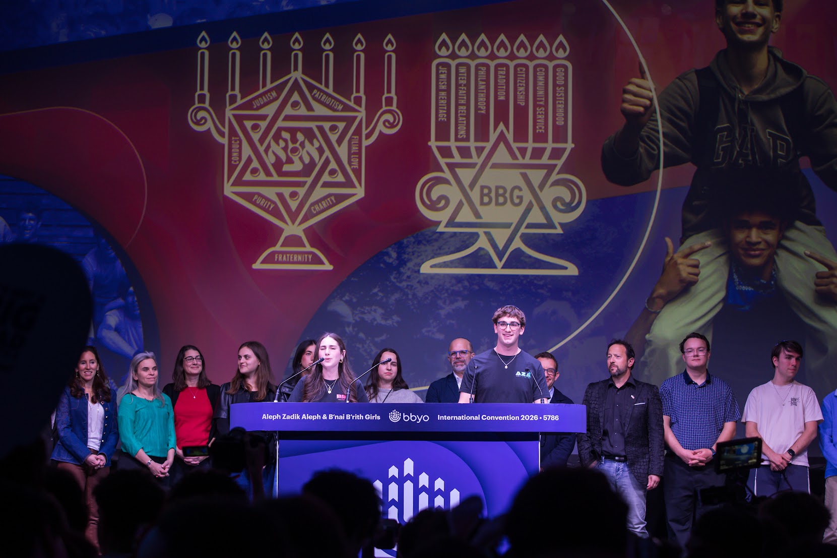 A diverse crowd of people celebrating at a concert, raising their hands and cheering.
