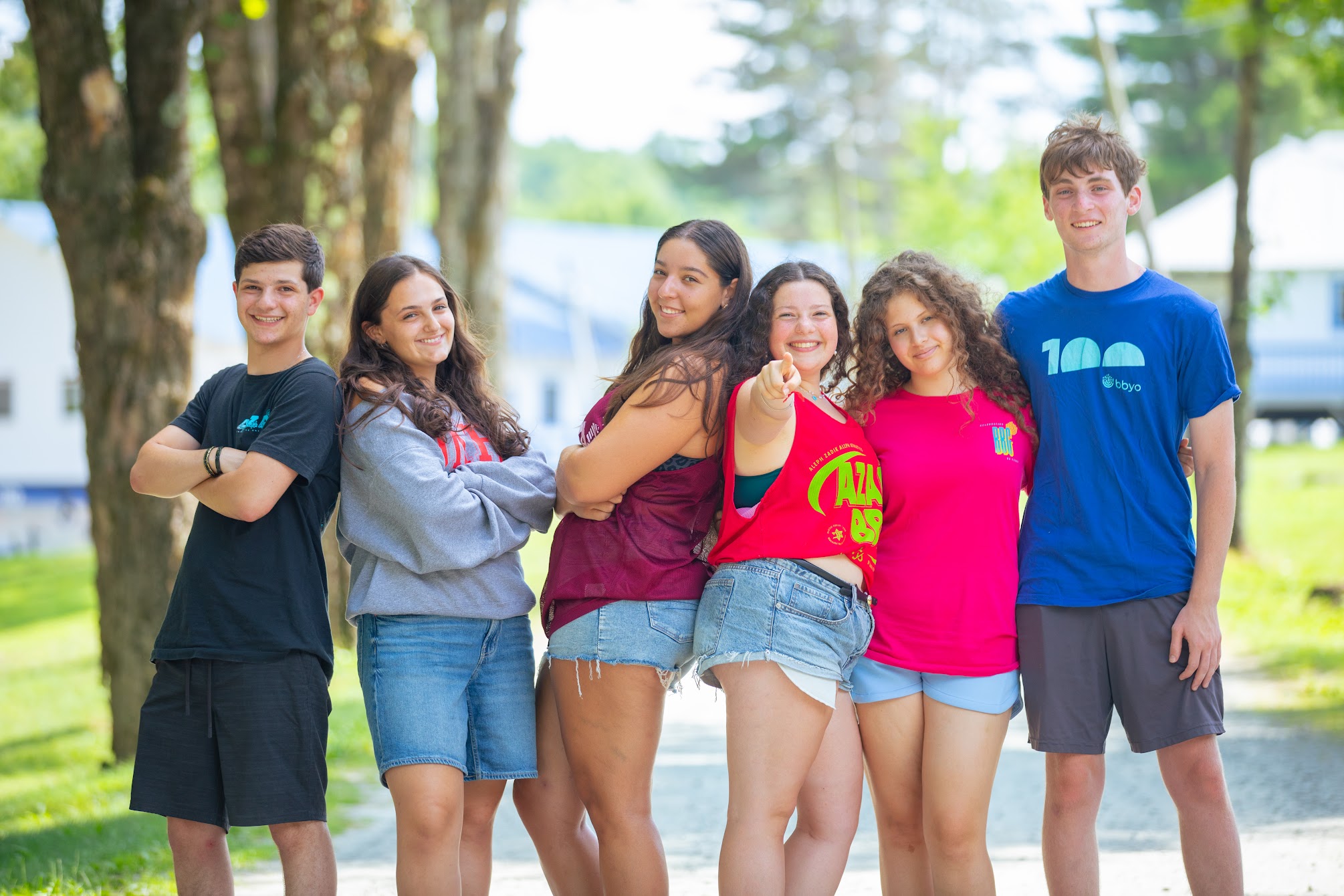 A diverse group of young adults jumping with excitement in a lush green garden during a community event.